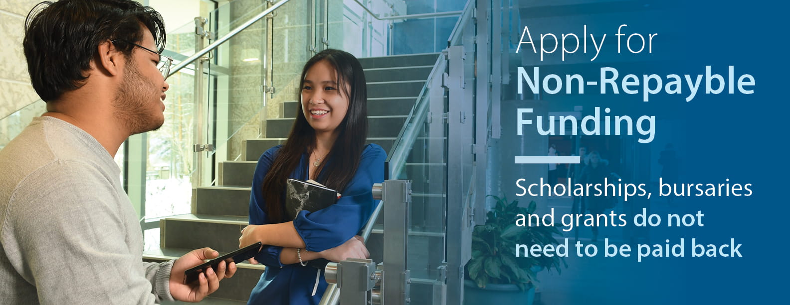 Two students, one male and one female, standing and having a conversation on the stairs. Text reads "Apply for Non-Repayable Funding. Scholarships, bursaries and grants do not need to be paid back." 