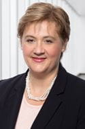 A woman with light brown hair, wearing a suit, poses for a portrait.