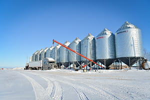 Grain bins in winter with truck and auger in front