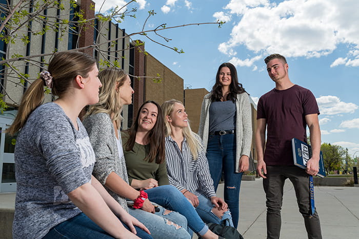 Group of university students standing or sitting outside on campus