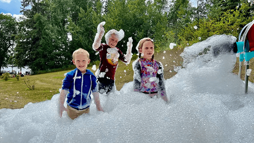 Children laughing and dancing in bubbles outside