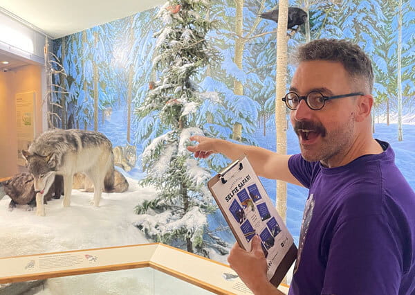 RSM gallery interpreter points to winter themed display with a wolf. 