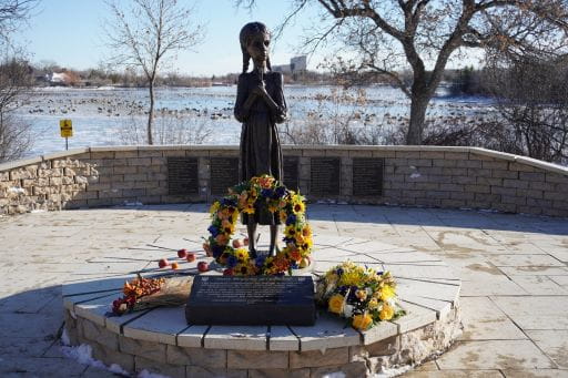 Bronze statue of a sad, young girl holding a wheat sheaf