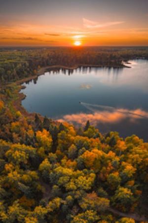 Lake photo with fall leaves with a setting sunset in the distance