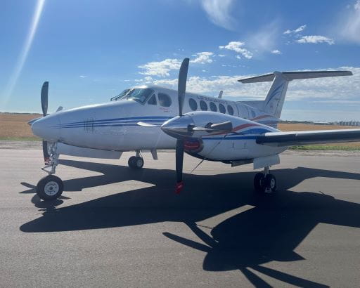 White airplane on a runway, blue sky with white clouds in the background