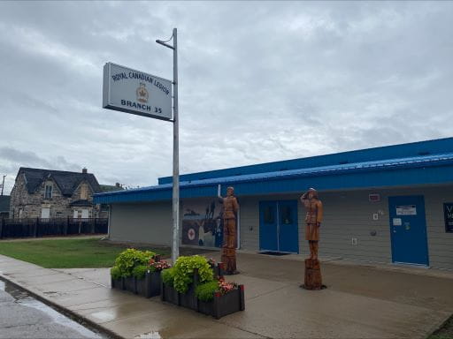 Image showing exterior of the Royal Canadian Legion Branch 35 in Fort Qu’Appelle, with two commemorative bronze statues depicting a Canadian Serviceman and Woman at attention