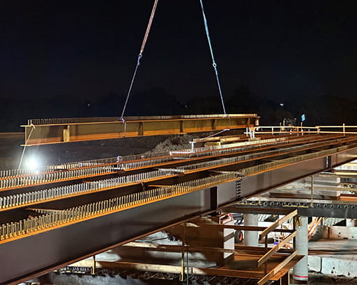 Steel girder being moved as part of highway overpass construction