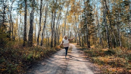 Woman walking down path during fall